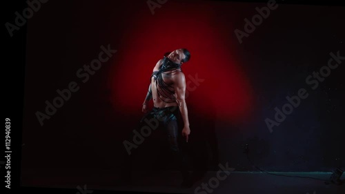 Muscular sexy naked man dancing in the studio on red light background