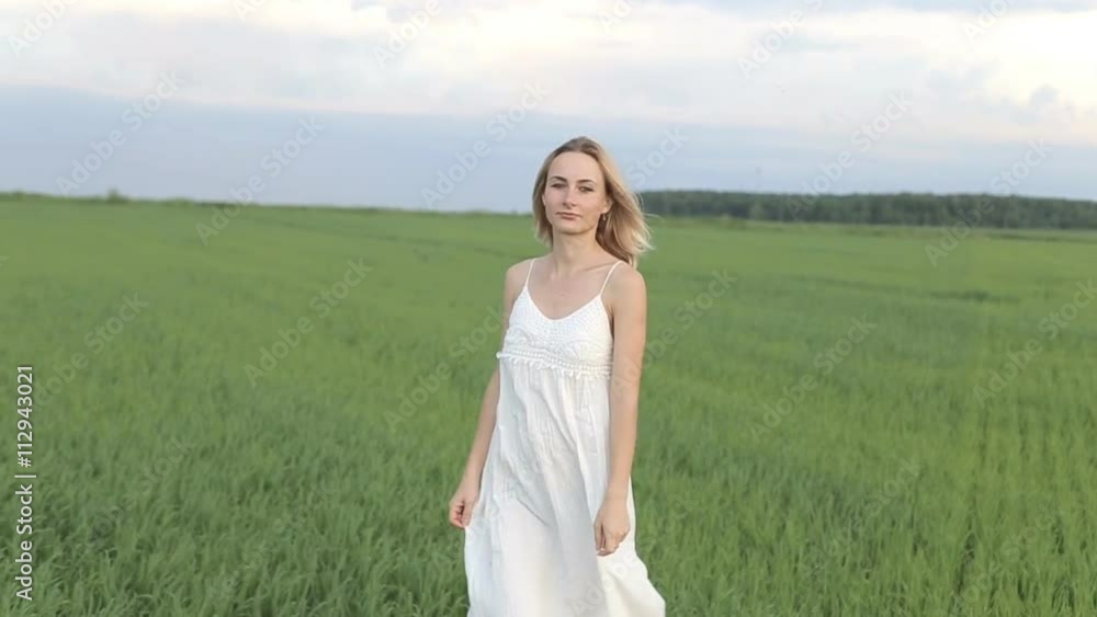 Young Woman Walking Through Summer Field, Rear View Young Woman Walking Through Summer Field, Rear View
