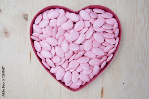Pink sugar covered almonds surface top view heart symbol © OceanProd