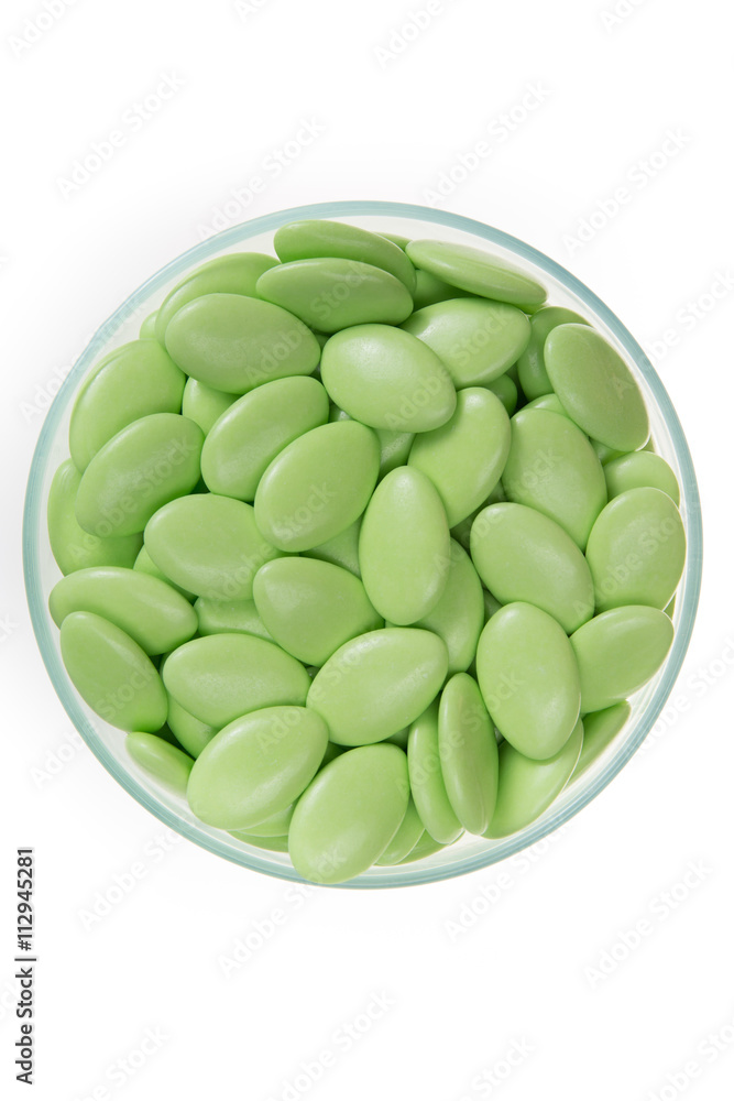 Green dragees, sugar coated pills at glass dish, isolated Green dragees, sugar coated pills at glass dish, isolated