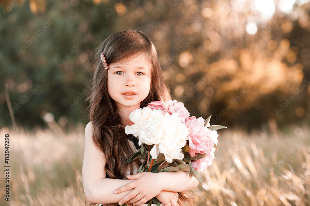 Cute baby girl 4 5 year old holding flowers in field. Looking at