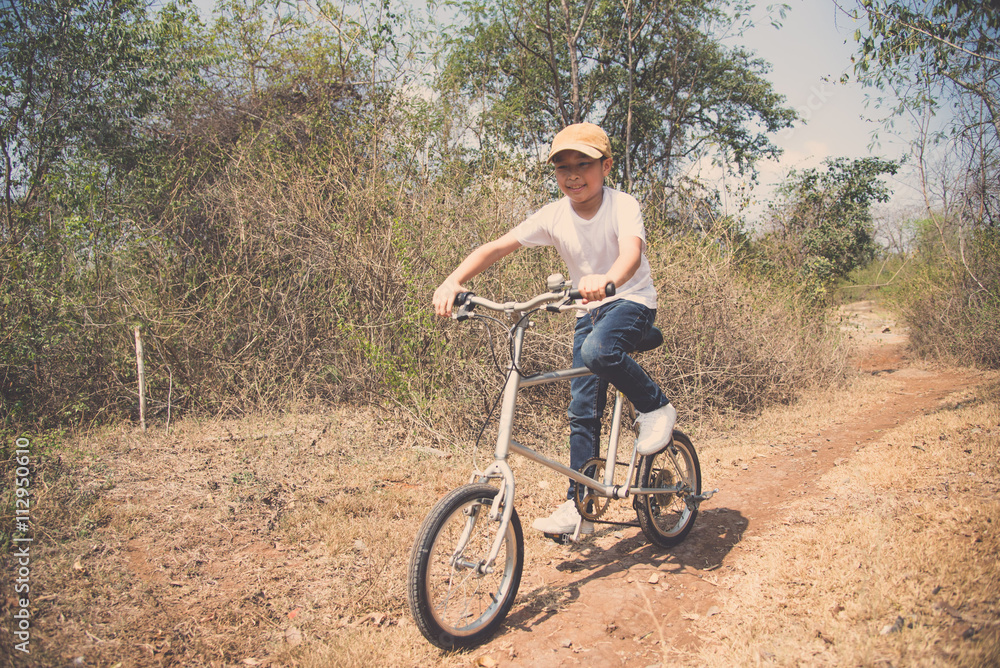 Fototapeta premium Little boy ride bicycle on the rock road.