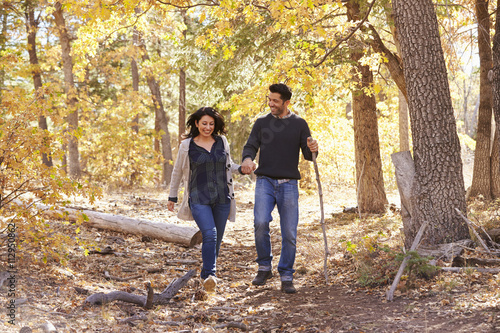 Smiling Hispanic couple walk in a forest holding hands © Monkey Business