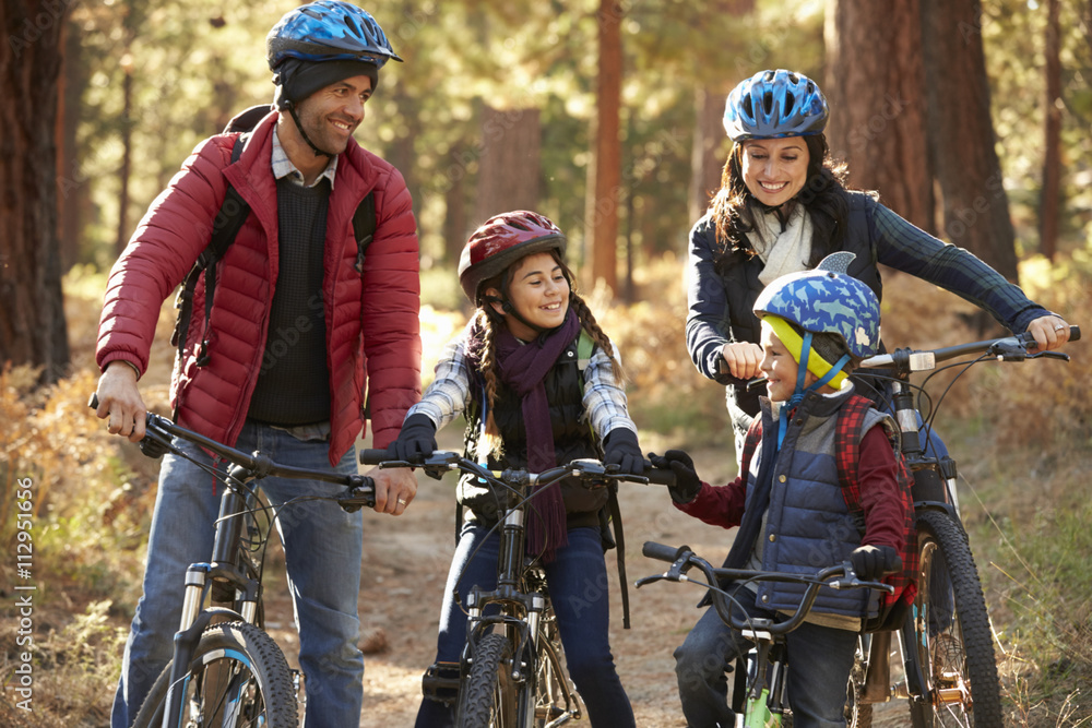 Fototapeta premium Hispanic family on bikes in a forest looking at each other