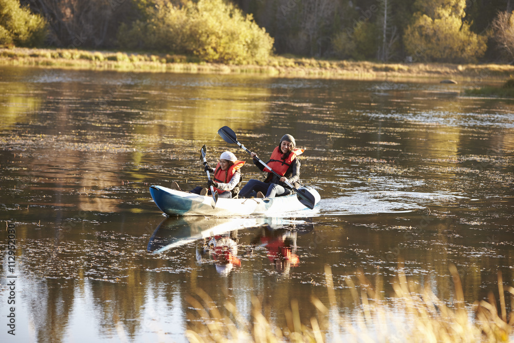 Mother and daughter kayaking together on a lake, front view
