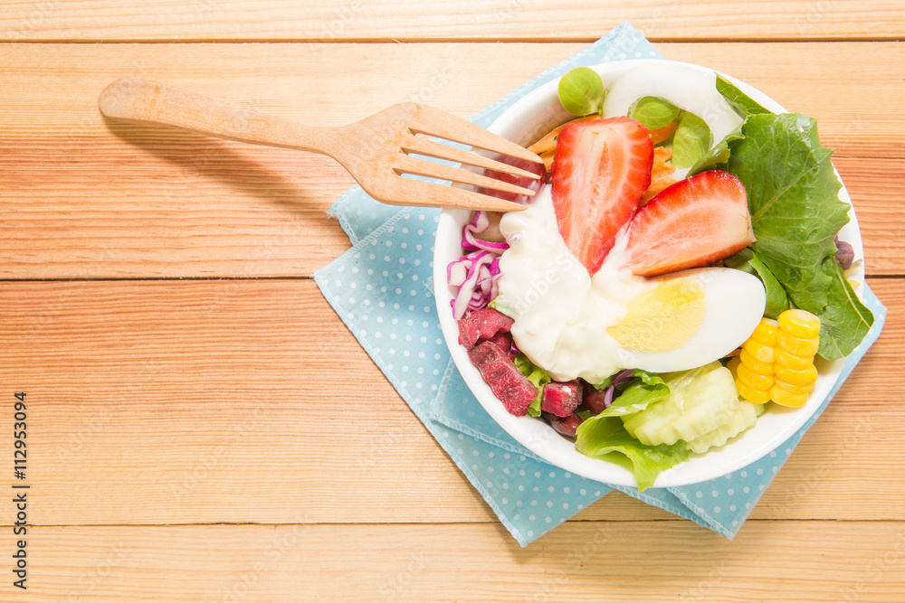 Fresh healthy salad with frok on wooden table. View from above w Fresh healthy salad with frok on wooden table. View from above w