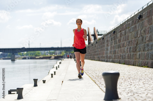 Fototapeta Naklejka Na Ścianę i Meble -  Fit woman jogging by the river.
