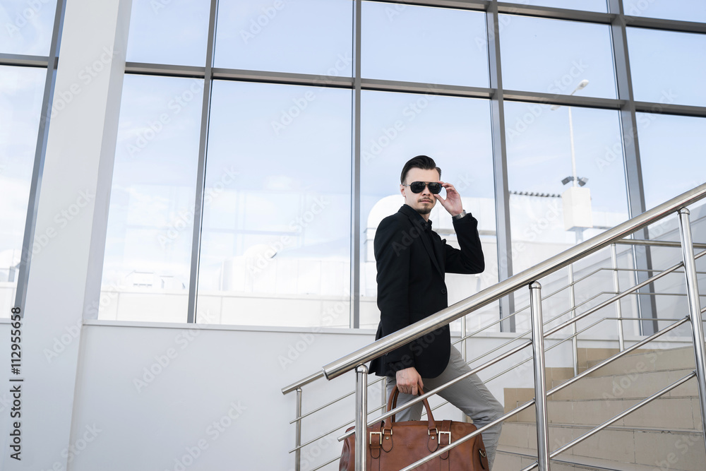 Portrait of stylish man looking at camera while walking on steps Portrait of stylish man looking at camera while walking on steps