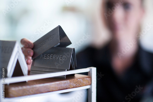 Waitress taking metal Reserved sign from rack