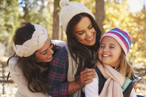 Female parents and daughter in a forest looking at each other