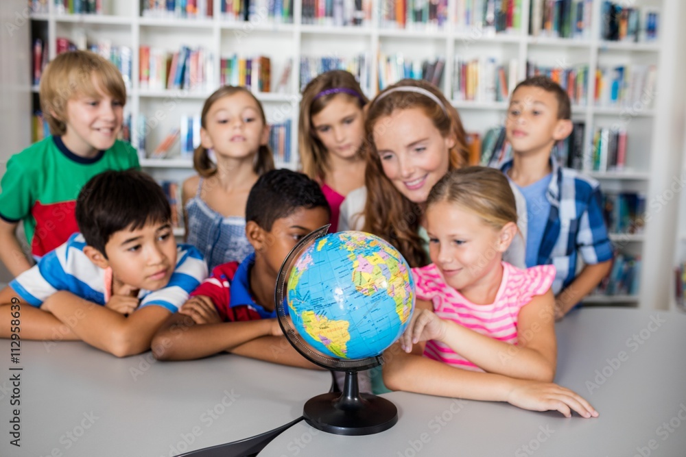 Fototapeta premium Teacher and pupils looking at a globe