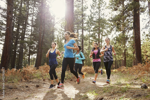 Group of young adult women running in a forest, close up