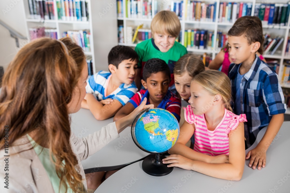 Fototapeta premium Teacher and pupils looking at a globe