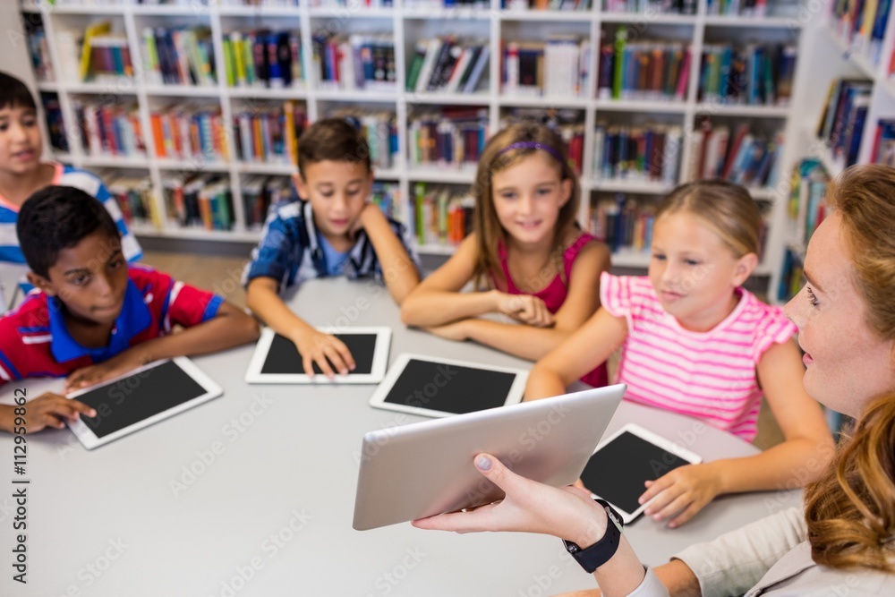 Young pretty teacher having lesson to children with their tablet Young pretty teacher having lesson to children with their tablet