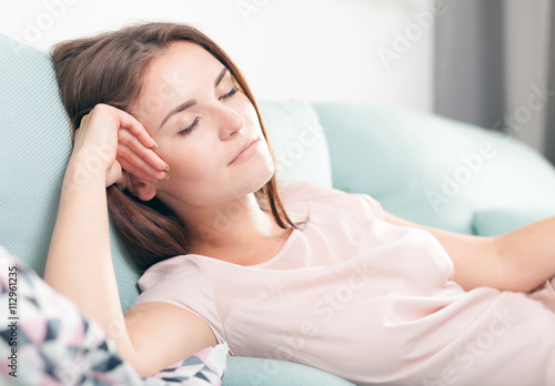 Young woman lying on couch and sleeping at home. Casual style indoor shoot