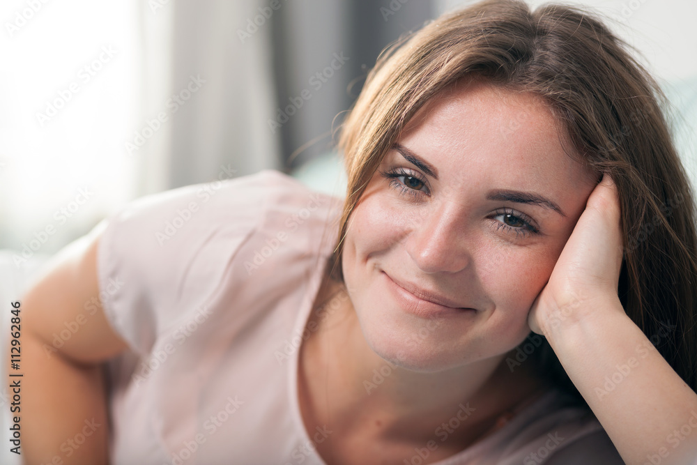 Happy young woman lying on couch at home and smiling. Casual style indoor shoot Happy young woman lying on couch at home and smiling. Casual style indoor shoot