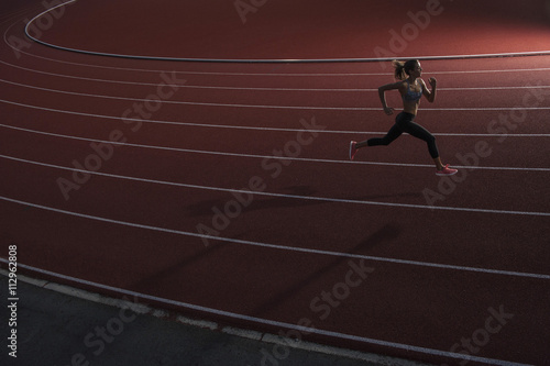 High angle view of young female athlete running on race track
