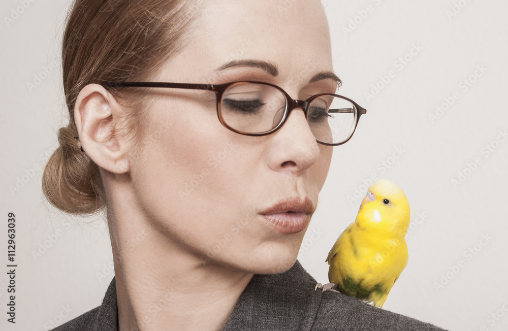 Beautiful woman looking at yellow budgerigar perching on shoulder against white background Beautiful woman looking at yellow budgerigar perching on shoulder against white background