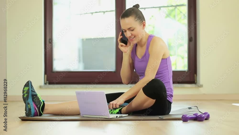 Young sporty woman working with laptop and phone in a bright room Young sporty woman working with laptop and phone in a bright room