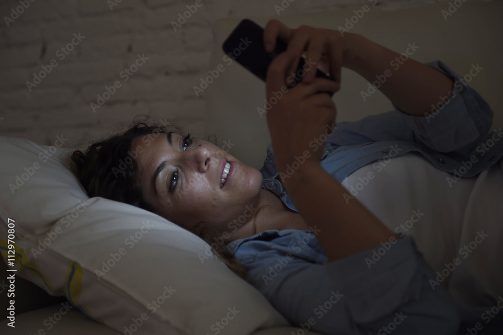 young beautiful woman lying on home couch using mobile phone texting smiling happy - obrazy, fototapety, plakaty 