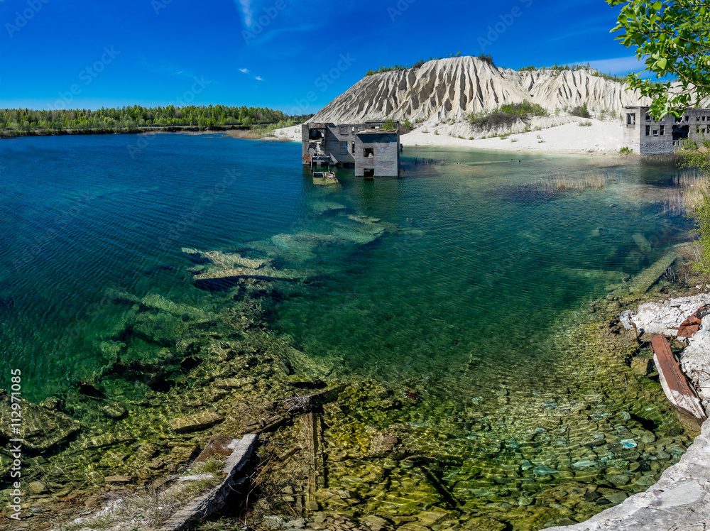 Obraz premium Abandoned mines and hauses. Quarry and old prison architecture. Crystal clear blue water, lake and mountain. The ashes dunes in Estonia, Europe.