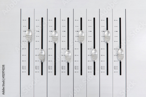 music mixer slider buttons on metallic casing forming an alternate pattern with small amplitude