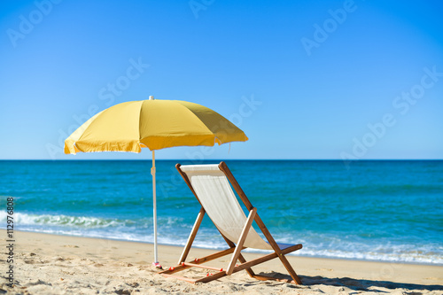 Yellow umbrella and wooden chair on Atlantic sandy beach