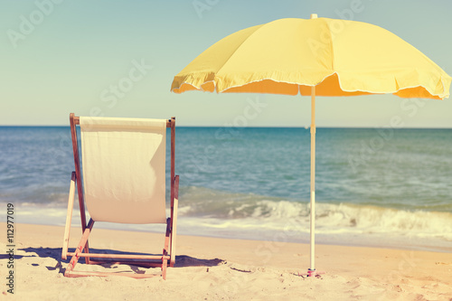 Back View Of Deckchair  Sun Lounger Under Umbrella On Sand Beach. 