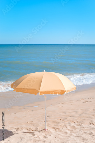 Yellow parasol on desert ocean beach over blue sky © aquar