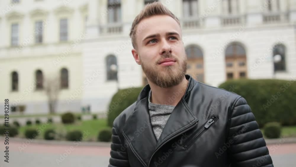 A man wearing trendy clothes using his cell phone trying to hide it from camera. A man wearing trendy clothes using his cell phone trying to hide it from camera.