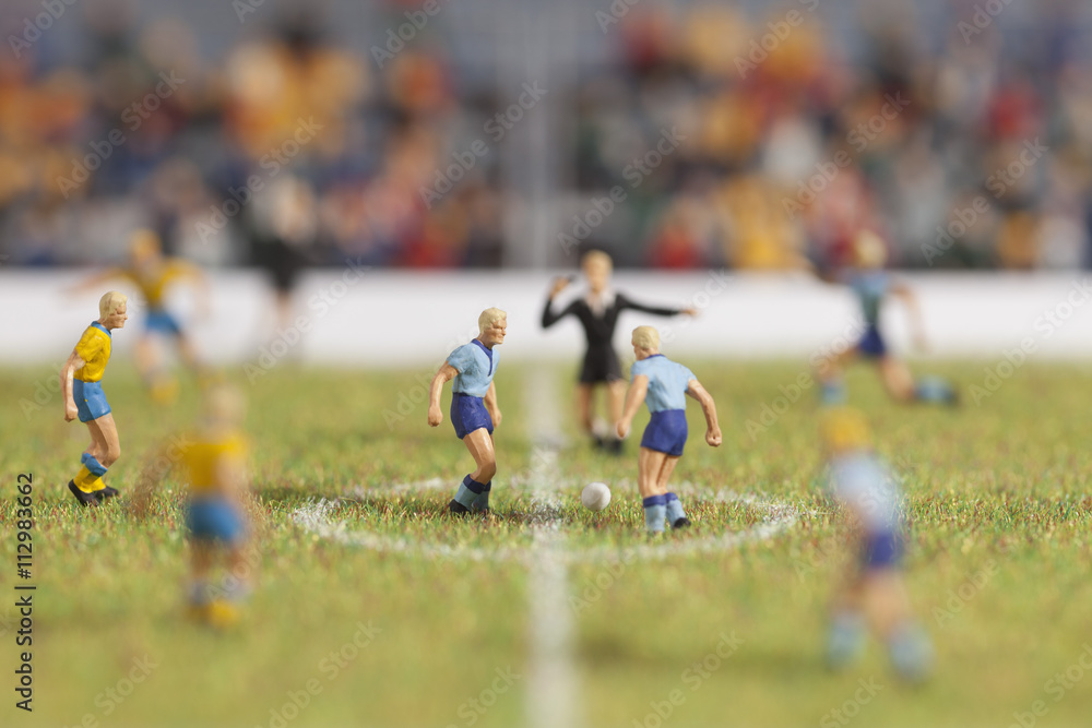 Miniature soccer player figurines at the kickoff of a soccer match