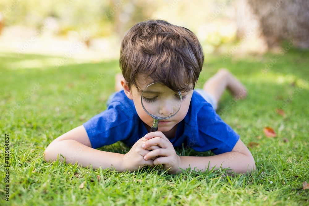 Boy examining grass with a magnifying glass Boy examining grass with a magnifying glass