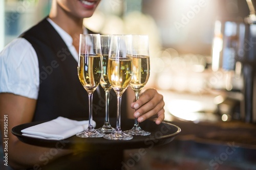 Mid section of waitress holding tray with champagne