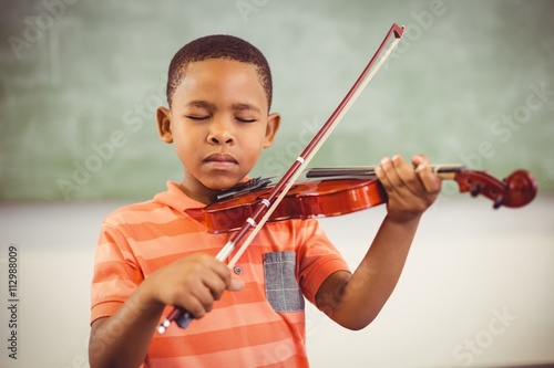 Schoolboy playing violin in classroom