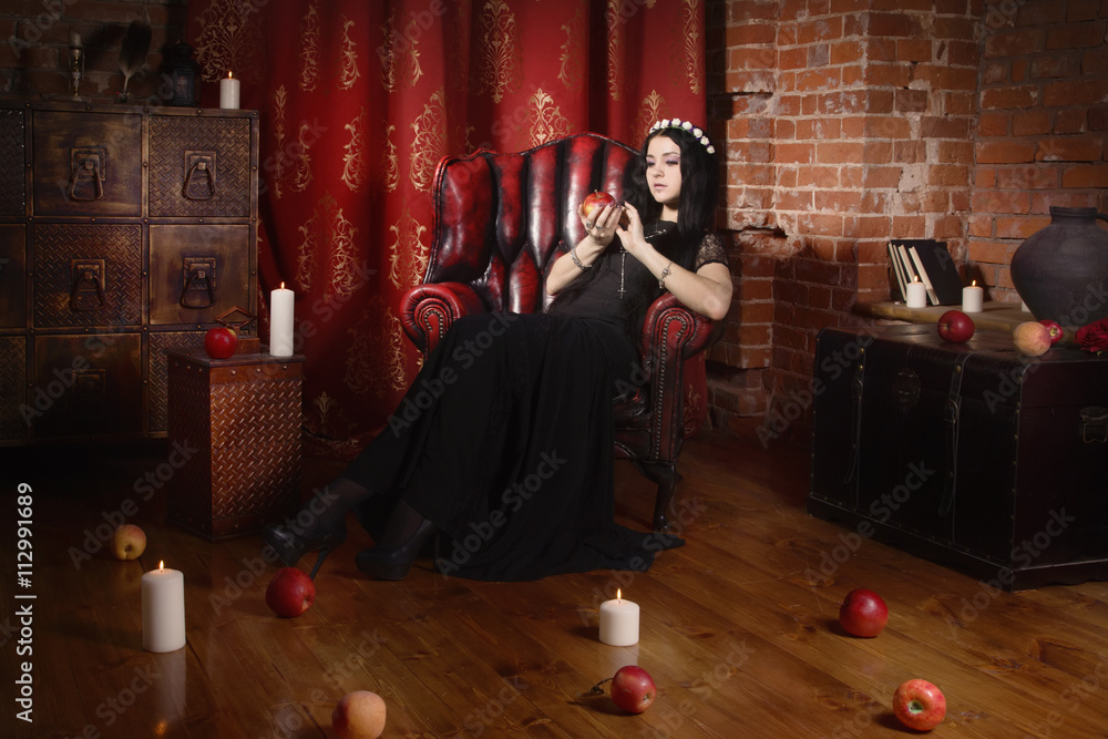 Beautiful witch in a black in the dark gothic interior