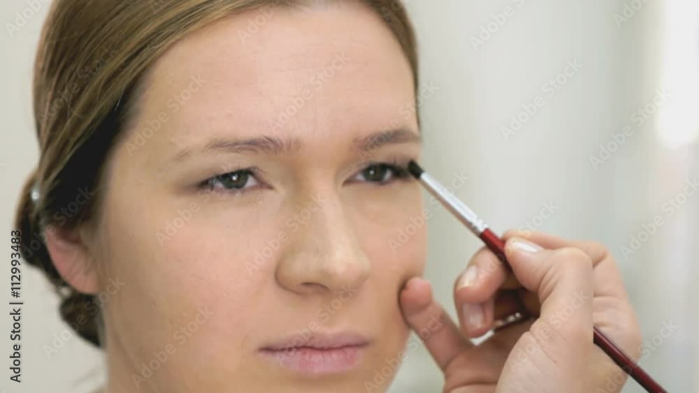 Makeup artist making make-up for young model Makeup artist making make-up for young model