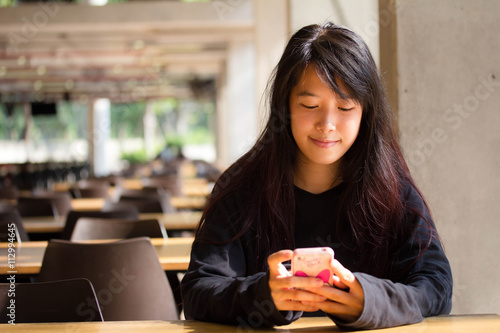 asia thai teenager Women black T-Shirt using her smart phone. photo