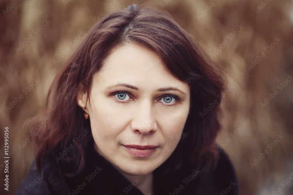 Closeup portrait of beautiful middle age white caucasian brunette woman with green eyes in coat jacket on fall autumn day outside looking in camera on yellow rye background Closeup portrait of beautiful middle age white caucasian brunette woman with green eyes in coat jacket on fall autumn day outside looking in camera on yellow rye background