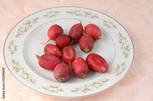 Whole raw radishes on white plate
