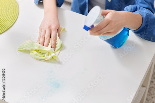 Young woman cleaning the table with a cloth