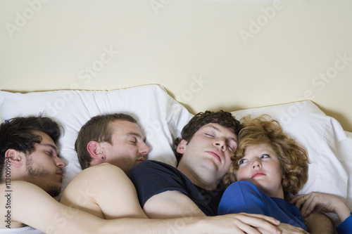 Four friends lying in a bed together