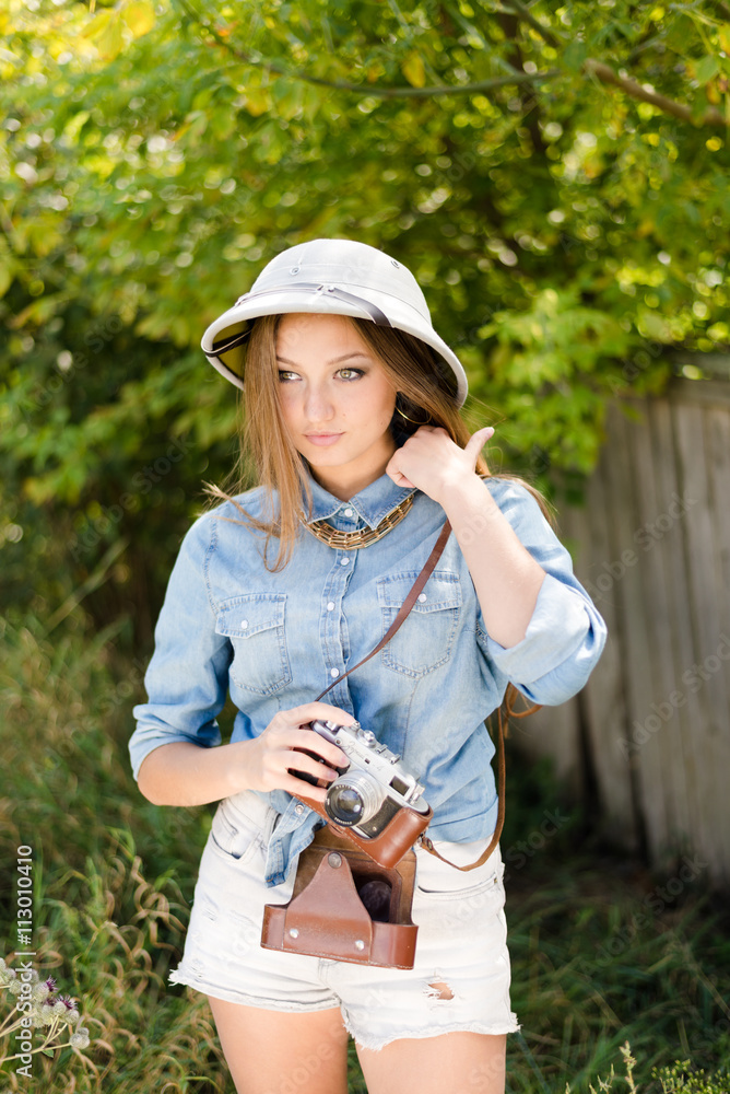 Φωτογραφία Young beautiful woman in pith hat taking pictures on retro camera on green trees