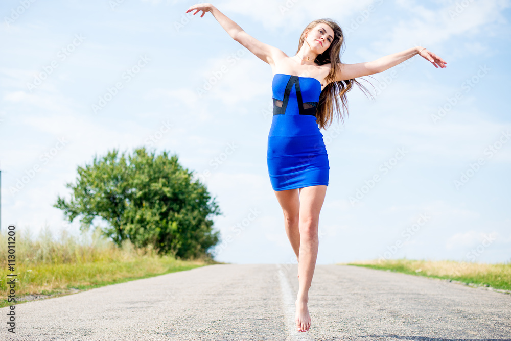 Obraz premium exciting flying like bird: portrait of beautiful brunette young woman having fun jumping high on the road on blue sky outdoors copy space background
