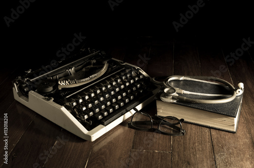 Stethoscope with eyeglasses book and typewriter.