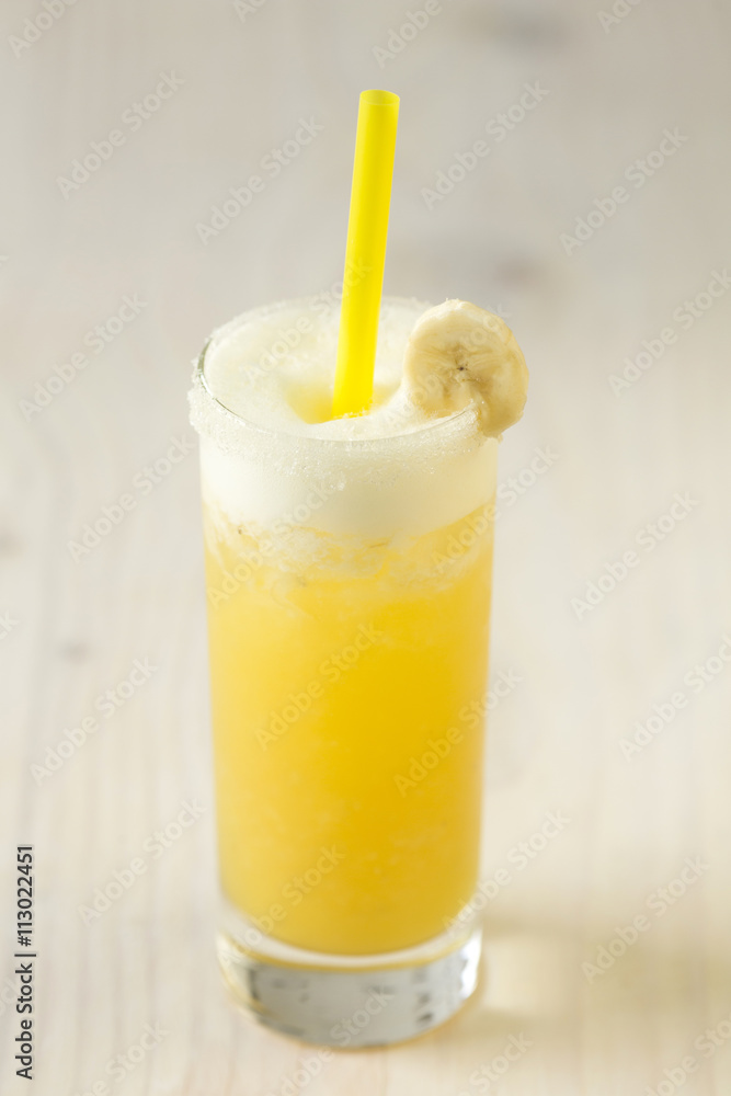 Yellow lemonade with banana in a glass on table close-up Yellow lemonade with banana in a glass on table close-up