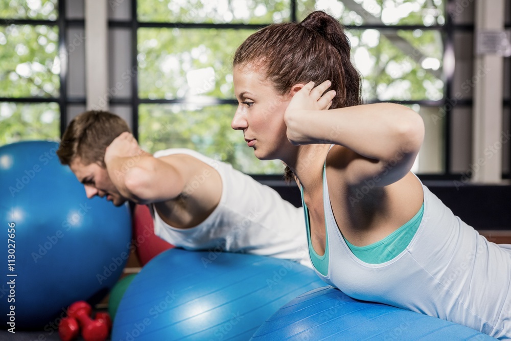 Man and woman working out on fitness ball
