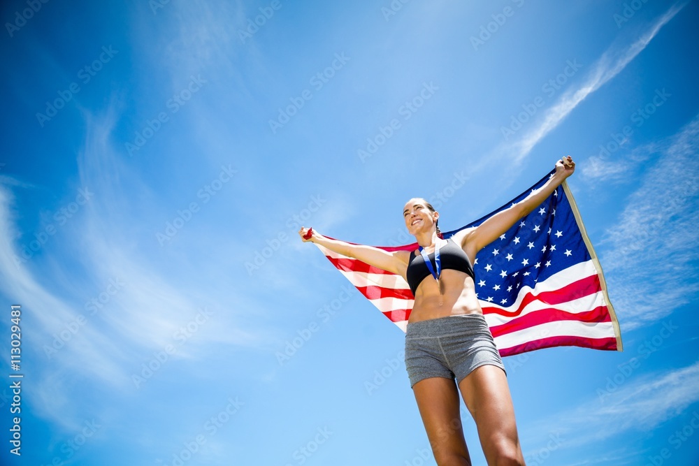 Happy female athlete holding up american flag 