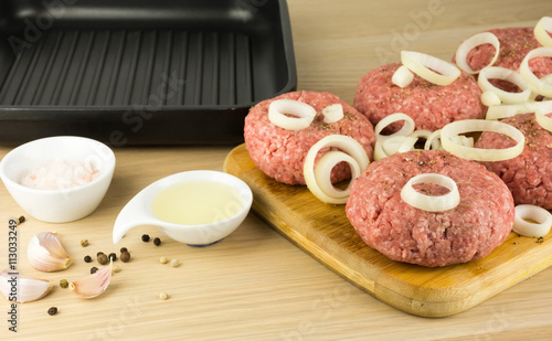 raw burgers, beef on a cooting board, frying pan on woogen backg photo