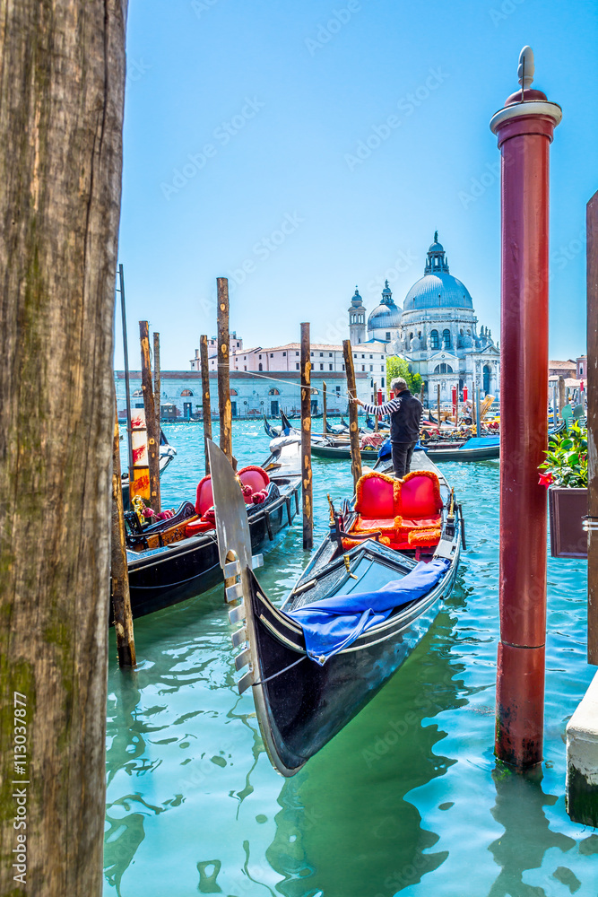 Fototapeta premium Wenecja turystyczna atrakcja Włochy. / Widok na stację dokującą gondoli i kościół Santa Maria di Salute w tle, wyjątkowe miasto turystyczne Wenecja, Włochy.