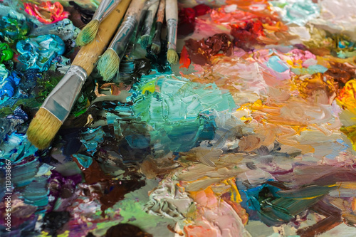 artist's palette with oil paints and brushes used for painting a photo